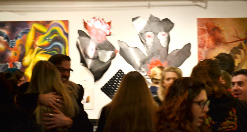 A group of people standing around in front of some paintings.